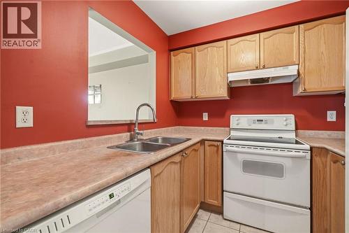 Kitchen featuring wood cabinetry, a double basin stainless steel sink with a high-arc faucet, and white appliances including a dishwasher and electric range with an overhead exhaust fan - 4413 Peter Drive, Burlington, ON 