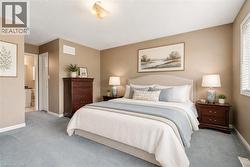 VIRTUALLY STAGED Carpeted room featuring a window with blinds, a ceiling-mounted light fixture, and a doorway leading to another room - 