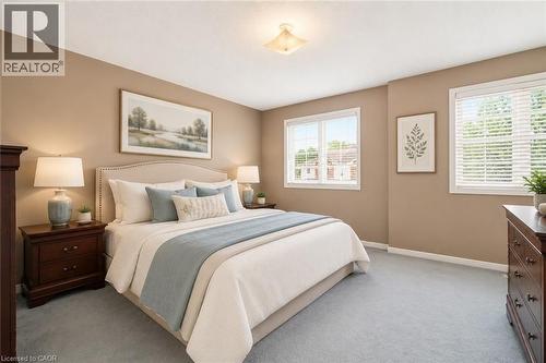 VIRTUALLY STAGED Spacious bedroom with light beige walls and soft blue carpeting - 4413 Peter Drive, Burlington, ON 