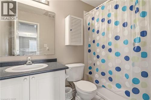 Bathroom featuring a white vanity with an integrated sink, dark countertop, and an overhead light fixture - 4413 Peter Drive, Burlington, ON 