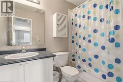 Bathroom featuring a white vanity with an integrated sink, dark countertop, and an overhead light fixture - 
