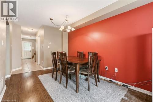 Dining area with wood-finish flooring, a contemporary chandelier, and a distinctive accent wall - 4413 Peter Drive, Burlington, ON 