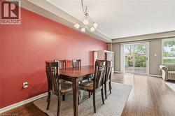 Bright interior space featuring a red accent wall, wood-finish flooring, and a contemporary chandelier - 