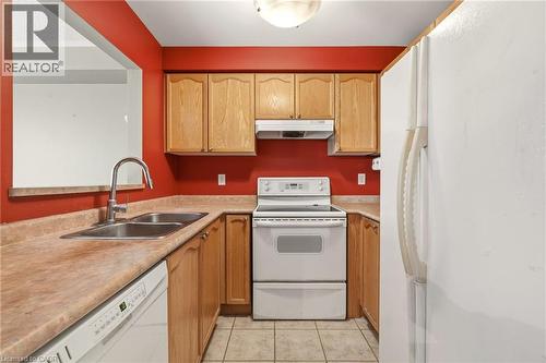 Kitchen featuring light wood cabinetry, a double basin stainless steel sink with a high-arc faucet, and white appliances including a dishwasher and range - 4413 Peter Drive, Burlington, ON 