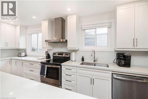 Contemporary kitchen featuring white shaker cabinetry, stainless steel appliances, a double basin sink, light-toned countertops, and subway tile backsplash - 39 Forestgate Drive, Hamilton, ON 