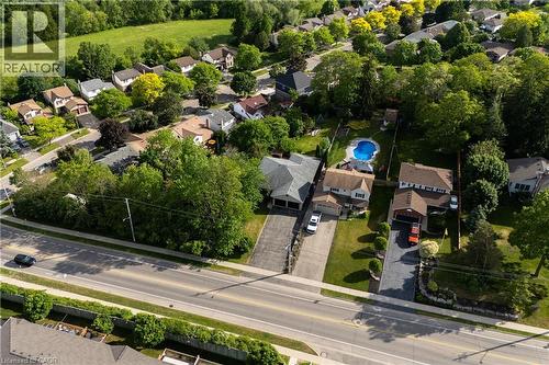 Residential property featuring a paved driveway, attached garage, manicured lawn, and mature trees - 907 Doon Village Road, Kitchener, ON 