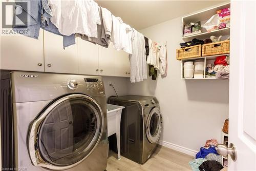 Dedicated laundry space featuring a utility sink, light wood-finish flooring, and ample built-in cabinetry for organized storage - 907 Doon Village Road, Kitchener, ON - Indoor Photo Showing Laundry Room