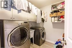 Dedicated laundry space featuring a utility sink, light wood-finish flooring, and ample built-in cabinetry for organized storage - 