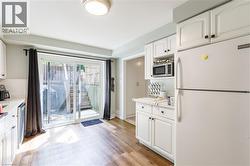 Kitchen area featuring wood-finish flooring, white cabinetry with black hardware, and a sliding glass door - 