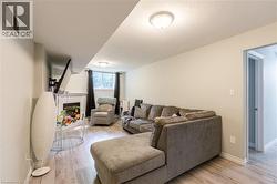 Living area featuring wood-finish flooring, a corner fireplace with white mantel, recessed lighting, and a visible hallway entrance - 