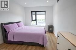 Room with a large window, recessed lighting, white walls, and wood-finish flooring - 