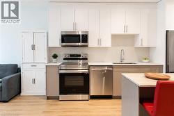 Modern kitchen featuring white upper cabinetry, two-tone lower cabinetry, and stainless steel appliances - 