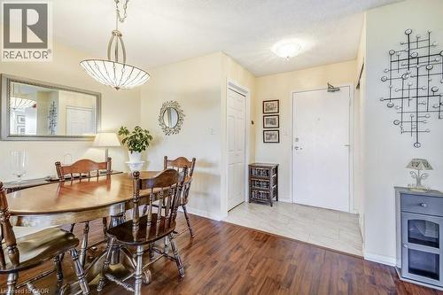 Open concept dining area featuring wood-finish flooring, a contemporary chandelier, and a spacious entryway with tile flooring - 1201 North Shore Boulevard E Unit# 706, Burlington, ON - Indoor Photo Showing Dining Room