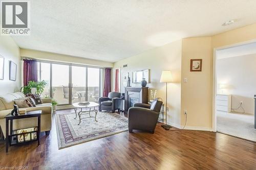 Spacious living area featuring wide plank wood-finish flooring, a contemporary fireplace with a dark mantel, and a multi-panel sliding glass door opening to a private balcony - 1201 North Shore Boulevard E Unit# 706, Burlington, ON - Indoor Photo Showing Living Room