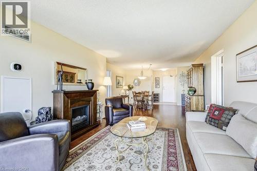 Living area featuring wood-finish flooring, a fireplace with a dark wood mantel, and light-colored walls - 1201 North Shore Boulevard E Unit# 706, Burlington, ON - Indoor Photo Showing Living Room With Fireplace