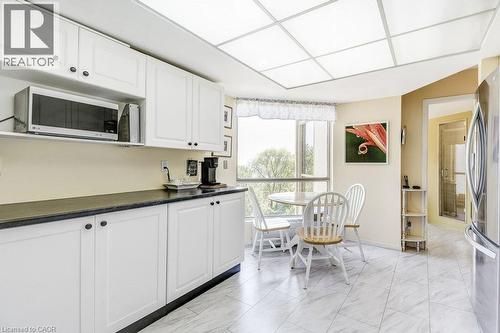 Kitchen featuring white cabinetry, dark countertops, a window with natural light, tiled flooring, and a full-size refrigerator - 1201 North Shore Boulevard E Unit# 706, Burlington, ON - Indoor