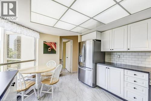 Kitchen featuring white cabinetry, subway tile backsplash, stainless steel refrigerator, dark countertops, and tile flooring - 1201 North Shore Boulevard E Unit# 706, Burlington, ON - Indoor