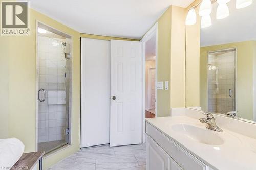 Full bathroom featuring a glass-enclosed shower with white subway tile, a white vanity with a single basin sink, and a large wall-mounted mirror - 1201 North Shore Boulevard E Unit# 706, Burlington, ON - Indoor Photo Showing Bathroom