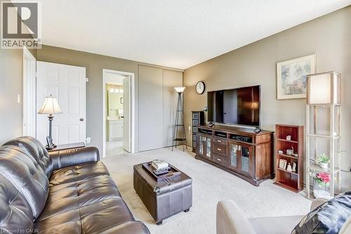 Carpeted living area featuring a neutral wall palette, white trim, and a white six-panel door - 1201 North Shore Boulevard E Unit# 706, Burlington, ON - Indoor Photo Showing Living Room