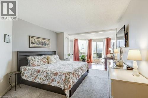 Spacious sleeping area featuring light gray walls and plush carpeting, opening to a bright alcove - 1201 North Shore Boulevard E Unit# 706, Burlington, ON - Indoor Photo Showing Bedroom