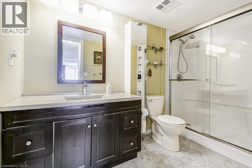 Full bathroom featuring a dark wood-finish vanity with an integrated sink, a framed mirror, and a walk-in shower with a glass sliding door - 1201 North Shore Boulevard E Unit# 706, Burlington, ON - Indoor Photo Showing Bathroom