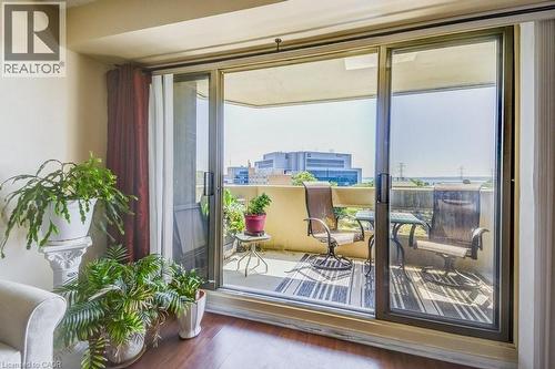 Sliding glass doors opening to a private balcony featuring a textured railing and an urban backdrop - 1201 North Shore Boulevard E Unit# 706, Burlington, ON - Indoor Photo Showing Other Room