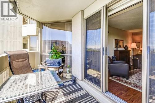 Private balcony featuring a painted concrete floor, striped area rug, and full-height glass sliding door - 1201 North Shore Boulevard E Unit# 706, Burlington, ON - 