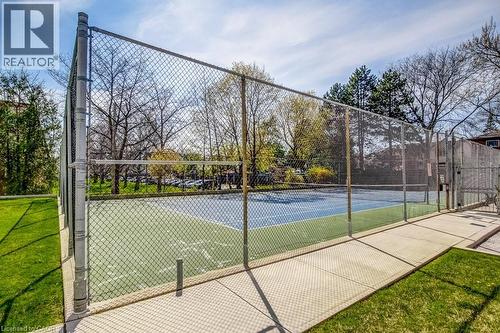 Tennis court with perimeter chain-link fencing, featuring a blue and green playing surface - 1201 North Shore Boulevard E Unit# 706, Burlington, ON - Outdoor
