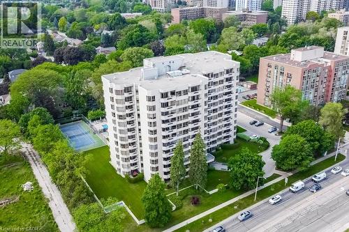 High-rise building featuring multiple balconies, surrounding green spaces, and an on-site tennis court - 1201 North Shore Boulevard E Unit# 706, Burlington, ON - Outdoor