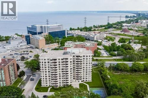High-rise residential building with multiple balconies, manicured green space, and an outdoor tennis court - 1201 North Shore Boulevard E Unit# 706, Burlington, ON - Outdoor With Body Of Water With View