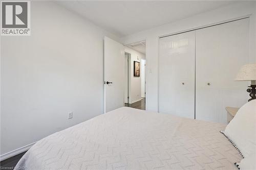 Bedroom featuring dark wood-finish flooring, white walls, and white bi-fold closet doors with brass-tone knobs - 600 White Elm Boulevard Unit# 9, Waterloo, ON 