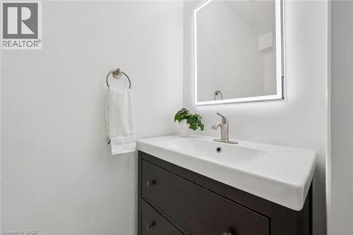 Bathroom vanity featuring a vessel sink, single-handle faucet, dark wood-finish cabinetry, and an illuminated mirror - 600 White Elm Boulevard Unit# 9, Waterloo, ON 