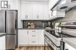 Contemporary kitchen featuring white shaker cabinetry with dark hardware - 