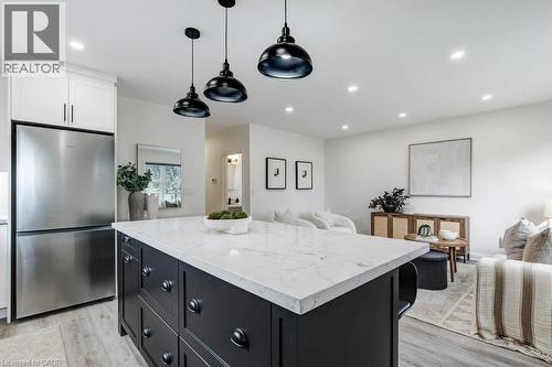 Kitchen island featuring a white countertop and dark cabinetry with matte black hardware - 202 Erindale Avenue, Hamilton, ON 