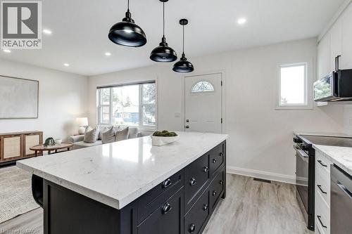 Kitchen island with a light-toned countertop, black cabinetry, and three pendant light fixtures - 202 Erindale Avenue, Hamilton, ON 