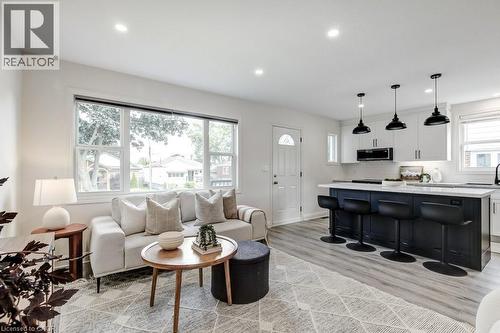 Open-concept living space featuring wood-finish flooring, recessed ceiling lighting, and a white entry door with an arched glass insert - 202 Erindale Avenue, Hamilton, ON 