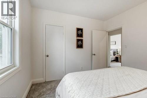 Bright interior space featuring white walls, gray carpet, a white door with a round doorknob, and a white-framed window - 202 Erindale Avenue, Hamilton, ON 