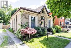 Brick exterior with white shutters, a covered front entry, and a paved driveway - 