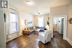 Spacious living area featuring wood-finish flooring, high ceilings, and two tall windows with arched transoms - 