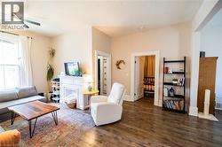 Living area with wood-finish flooring, a white decorative fireplace, and light-colored walls - 