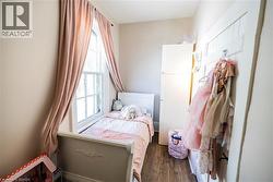 Room featuring wood-finish flooring, a double-hung window with a white frame, and light-colored walls - 