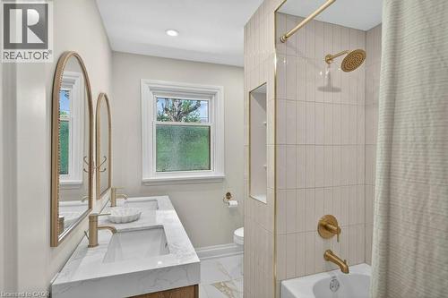 Bathroom featuring a dual vanity with white countertops, arched framed mirrors, and brushed brass fixtures - 603 Cornick Drive, Burlington, ON 