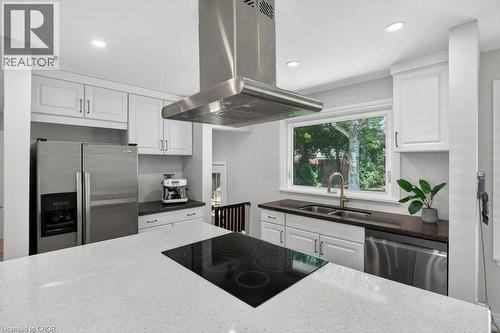 Kitchen featuring an integrated cooktop, stainless steel appliances, white cabinetry with contemporary hardware, and light-colored countertops - 603 Cornick Drive, Burlington, ON 