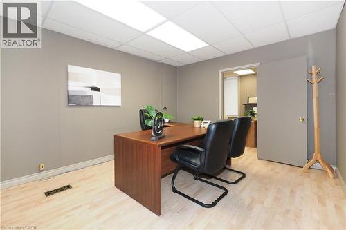 Office space featuring light wood-finish flooring, neutral-toned walls, and a suspended acoustic tile ceiling with integrated lighting panels - 731 King Street E, Cambridge, ON 