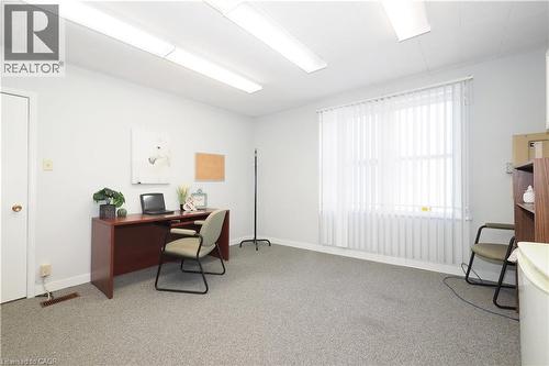 Versatile room featuring light gray walls, textured carpet flooring, and abundant overhead fluorescent lighting - 731 King Street E, Cambridge, ON 