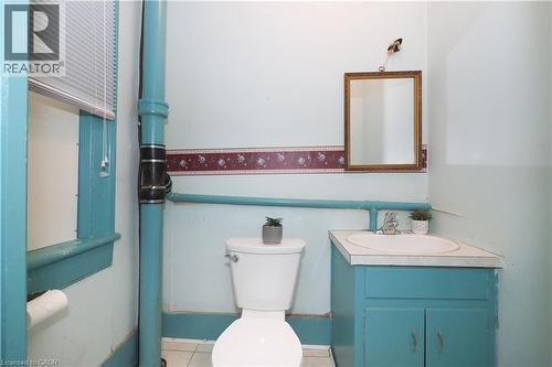 Bathroom featuring a corner vanity with an integrated sink, a wall-mounted mirror, and a window with blinds - 731 King Street E, Cambridge, ON 