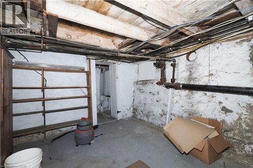 Exposed ceiling joists and utility lines featuring a concrete floor and painted stone foundation walls - 731 King Street E, Cambridge, ON 