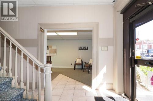 Entryway featuring a glass-paneled commercial door, white paneled walls, and ceramic tile flooring - 731 King Street E, Cambridge, ON 