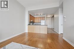 Open-concept living space featuring wood-finish flooring, light grey wall paint, and a kitchen with wood cabinetry and track lighting - 