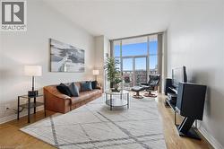 Living area featuring high ceilings, wood-finish flooring, a wall of windows, and a glass sliding door leading to a balcony - 